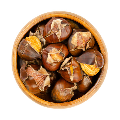 Freshly roasted chestnuts, in a wooden bowl. Popular autumn and winter street food in East Asia, Europe, and New York City. European sweet chestnuts, Castanea sativa, ready to eat roasted in the oven.