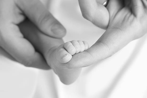 新しいボルンの赤ちゃんの父親との手 - human foot baby black and white newborn ストックフォトと画像