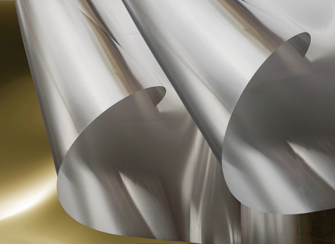 two sheets of thin aluminum foil metal material with rolled edges on a blurred background