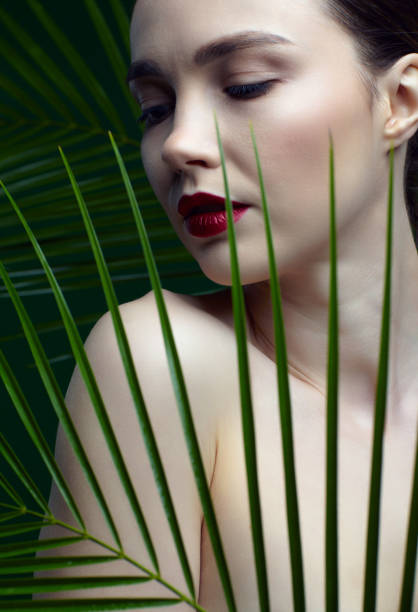 istock Romantic female with palm leaves on green background 1366342103