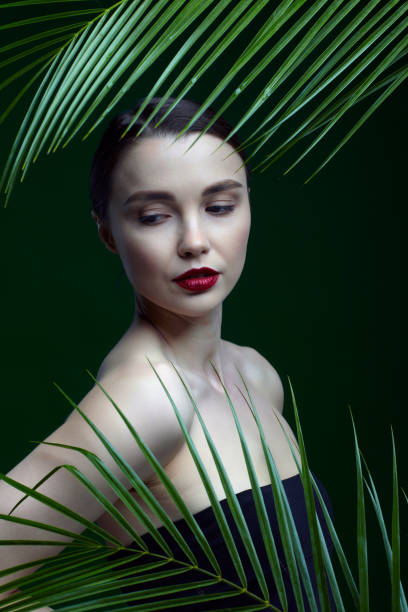 istock Romantic female with palm leaves on green background 1366342114