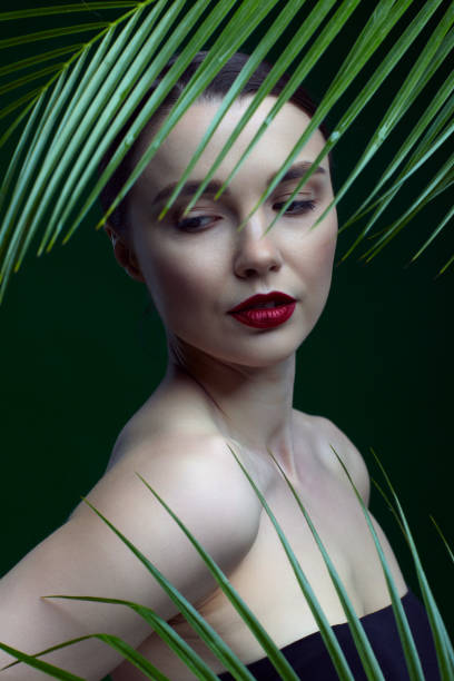istock Romantic female with palm leaves on green background 1366342120