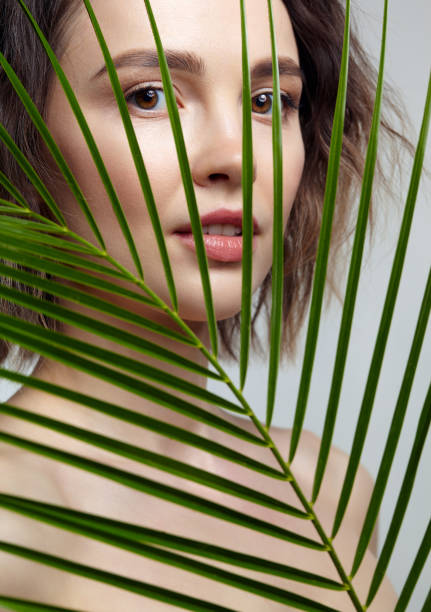 istock Romantic female with palm leaves on green background 1366342137