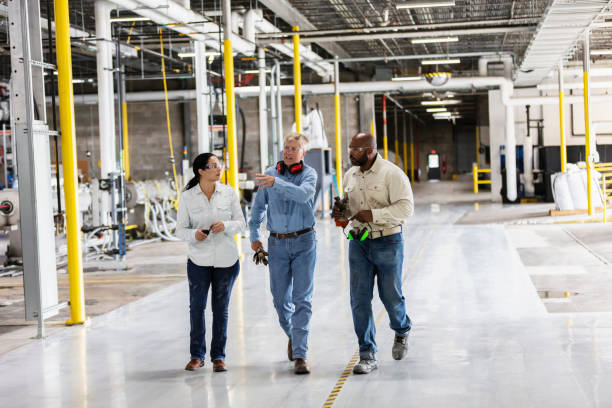 istock Three multiracial workers in factory, walking, talking 1366345459
