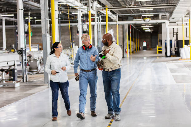 istock Three multiracial workers in factory, walking, talking 1366345460