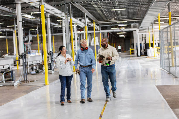 Three multiracial workers in factory, walking, talking