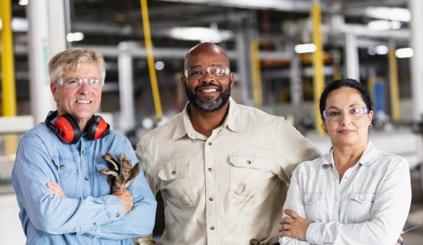 drei multirassische arbeiter in der fabrik - horizontal female with group of males posing looking at camera stock-fotos und bilder