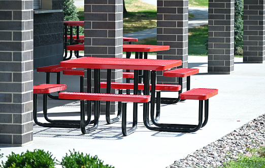 Red picnic tables in brick shelter.