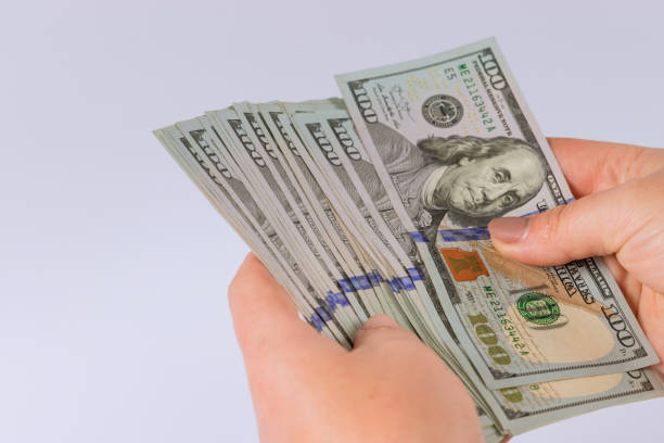 istock Woman hands counting US dollar banknotes the white background 1366350193