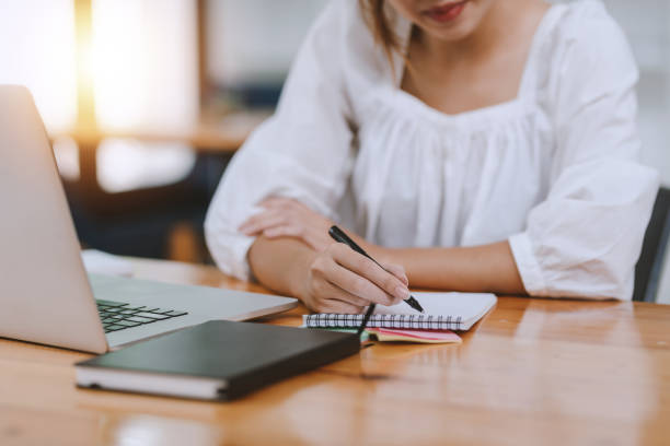 istock Close up of woman hand using pen taking notes in office. 1366350374