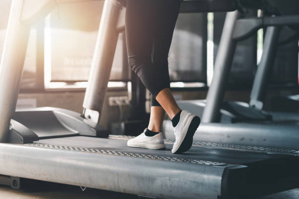 Close up. Woman running in machine treadmill at fitness gym club. stock photo