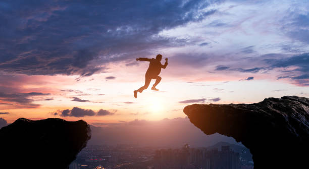 Silhouette of businessman jumping over the cliff Silhouette of businessman jumping over the cliff. leap of faith stock pictures, royalty-free photos & images