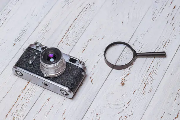 Photo of Old retro camera and magnifying glass on white boards