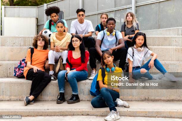 Multiracial Teenage Students Sitting On Steps In High School Outside Looking At Camera With Serious Expression Stock Photo - Download Image Now