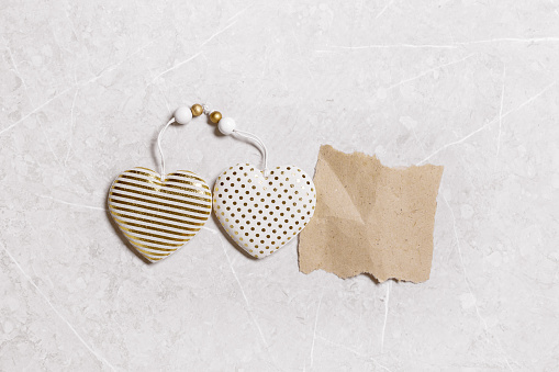 Valentines day concept. Soft toy hearts from linen cloth with gold color striped or dots on gray marble background. Valentine as torn paper craft with empty space. Paper mock up for text love message