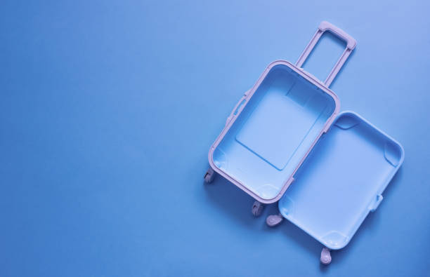 fully opened blue suitcase, on a blue background, top view. vacation, travel concept. copy space - suitcase imagens e fotografias de stock