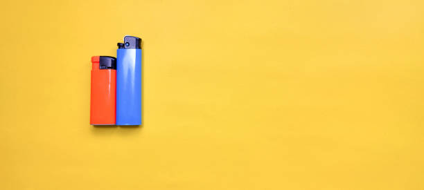 istock Blue and orange cigarette lighter on yellow background. 1366367330