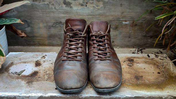 istock Old brown leather boots on cast bricks. Low leather boots. Casual leather shoes. Old brown leather shoes. 1366368064