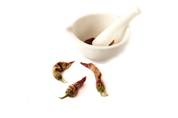 White porcelain set mortar and pestle with crushed hot red chili pepper and paprika. Isolated on white, top view, close-up.