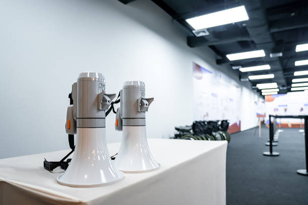 istock Two white - gray MEGAPHONE are laid on cream table in empty hall, ready to used for event corona virus vaccine booster in Bangkok, Thailand. 1366372952