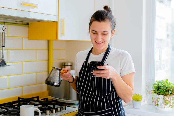 istock woman using smartphone and drinking coffee in kitchen. Concept happy morning leisure 1366373116