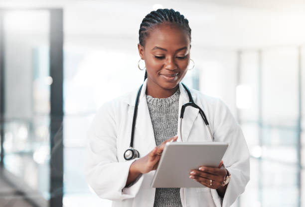 scatto di un giovane medico che utilizza una tavoletta digitale in un ospedale moderno - lab coat women one person female foto e immagini stock