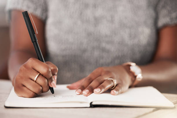 photo d’une femme d’affaires méconnaissable prenant des notes dans un livre dans un bureau moderne - liste photos et images de collection