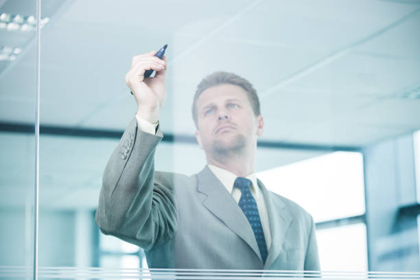 istock Businessman writing on glass wall with marker 1366379090