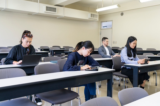 4 Asian students take classes in a university classroom.