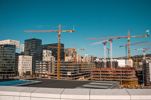 A lot of cranes are building tall buildings. Against the background of a modern quarter