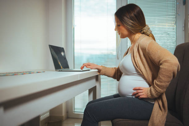 istock Pregnant woman using laptop at home 1366383210