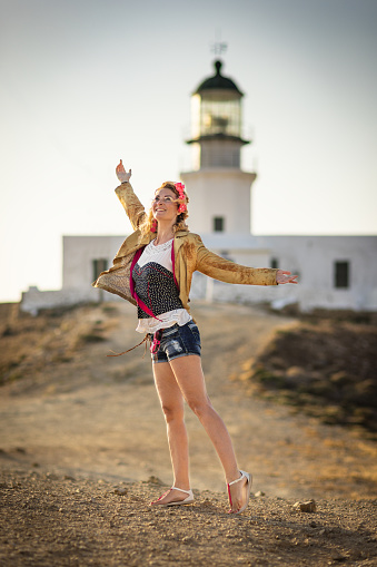 Woman enjoying time at Armenistis Lighthouse at NW part of Mykonos island, Cyclades, Greece in afternoon.