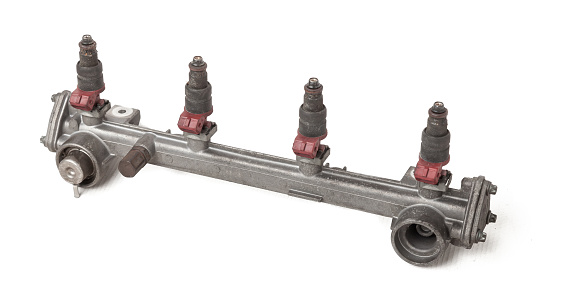 Close-up on a car fuel rail with injectors for supplying gasoline to a four cylinder engine on a white isolated background. Spare parts catalog.