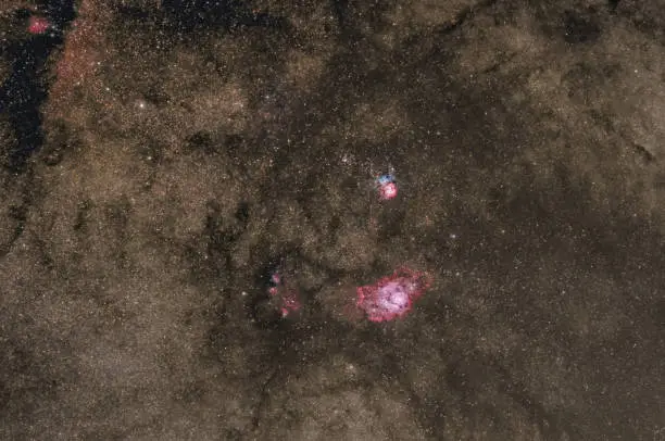 Lagoon (Messier 8, NGC 6523) and Trifid Nebula (Messier 20, NGC 6514) with part of the milky way on the night sky