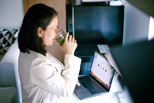 istock Asian woman working using laptop in the kitchen at home 1366389061