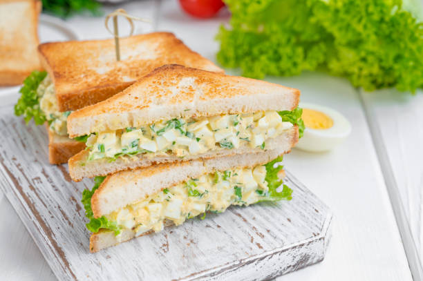 istock Egg salad sandwich with toasted bread and lettuce on a white wooden background. Selective focus 1366391711