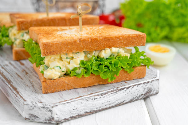 istock Egg salad sandwich with toasted bread and lettuce on a white wooden background. Selective focus 1366391712