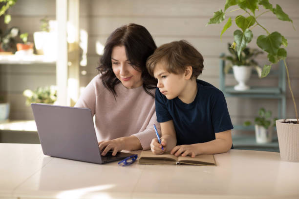 istock Mother and son are engaged in online school, sit in a laptop and make notes in a notebook 1366391724