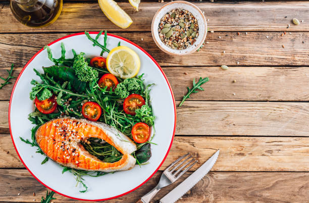 istock Salmon fish steak grilled and fresh vegetable salad on a wooden rustic table. 1366391754