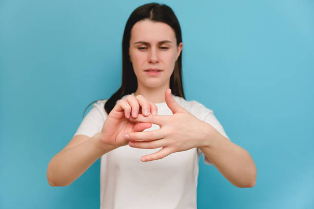 Close up ill female suffering from hand and finger joint pain with redness, model over blue background. Causes of pain include rheumatoid arthritis, carpal tunnel syndrome, trigger finger or gout Close up ill female suffering from hand and finger joint pain with redness, model over blue background. Causes of pain include rheumatoid arthritis, carpal tunnel syndrome, trigger finger or gout sclerosis stock pictures, royalty-free photos & images