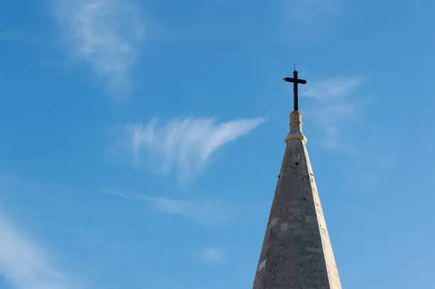 Top of stone church tower with holy cross, symbol of Catholicism, religious concept
