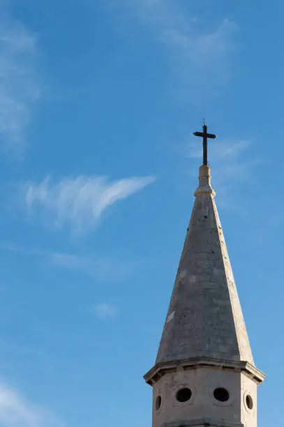 Top of stone church tower with holy cross, symbol of Catholicism, religious concept
