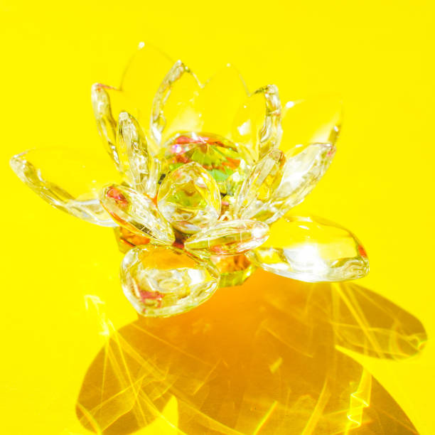 Beautiful crystal lotus flower on a yellow sunny table.