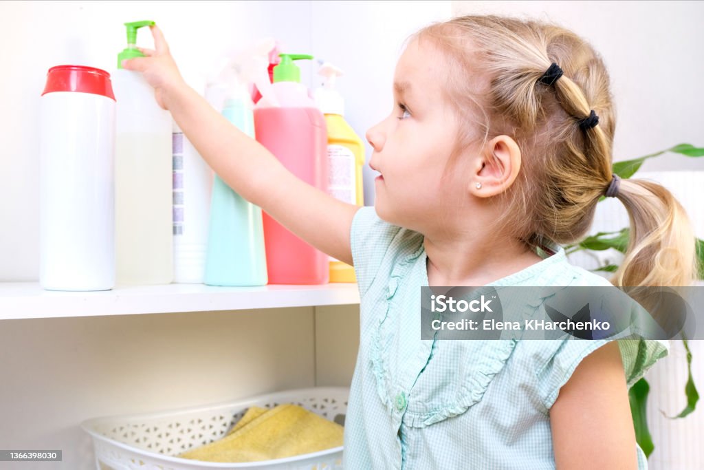 Toddler touches bottles of household chemicals, household cleaning products. Toddler touches bottles of household chemicals, household cleaning products. Dangerous situation Poisonous Stock Photo