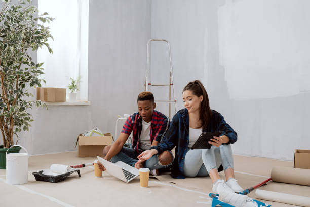 istock Interior designers construction managers architects work in newly constructed apartment building apartment renovation young woman and co-worker sit on floor with mugs of coffee laptop tablet plan 1366398172