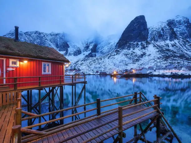 View on the house in the Lofoten Islands, Norway. Landscape in winter time during blue hour. Mountains and water. Travel image.