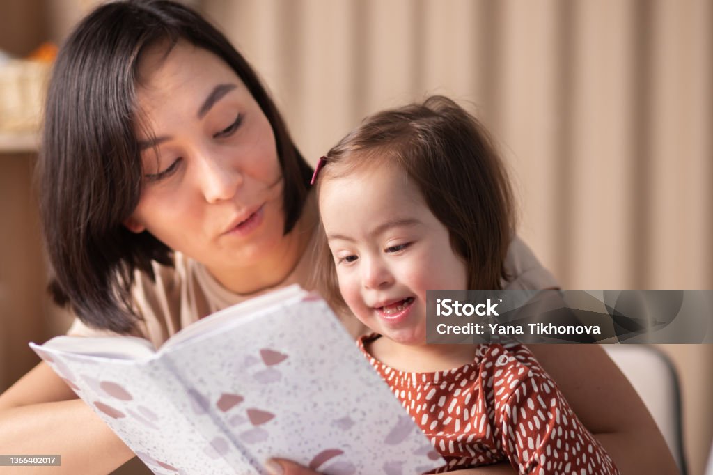 cute baby girl with down syndrome with book studying Disability Stock Photo