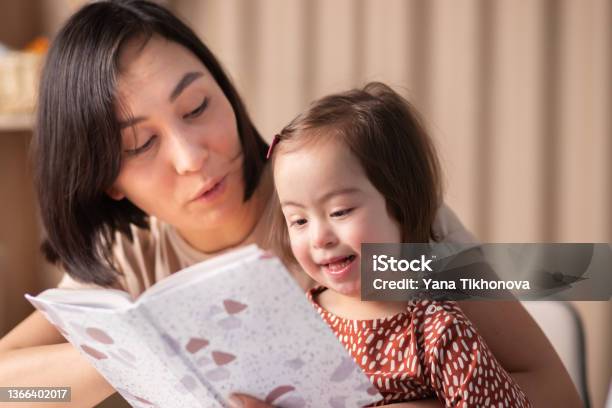 Cute Baby Girl With Down Syndrome With Book Studying Stock Photo - Download Image Now