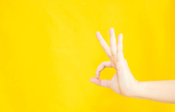 istock woman's hand with OK or agreement gesture  in copy space area for advertisement promotion or text on a yellow background 1366403382