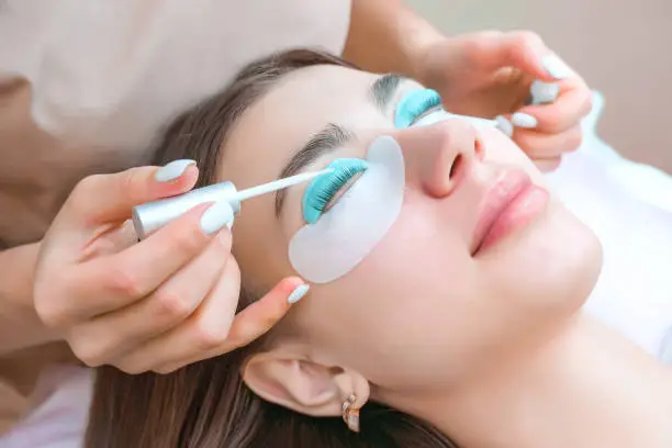 Young woman receiving eyelash lamination procedure in a beauty salon, close up